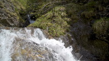 Slow motion of small waterfall in mountain stream in sunny spring nature
