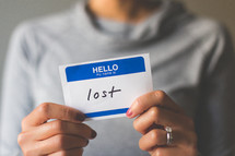 woman holding a name tag with the word lost 