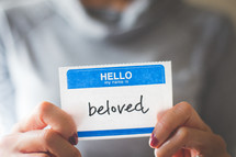 woman holding a name tag with the word beloved 