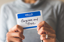 woman holding a name tag with the word forgiven and free 