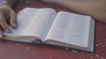 Close up of Bible on table with young man reading