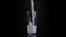 Milk pouring into a glass on a black background