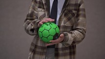 Man in plaid jacket holding a green soccer ball