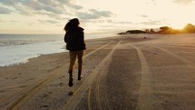 Girl walk on the beach at sunset near the ocean
