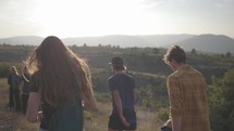 Small group of young adults hiking along a ridge or hilltop with mountains in the background