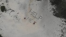 Help Me written in sand on a beach 