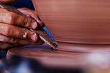 A closeup of a potter's hand sculpting clay