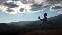 a man holding a cross praying on a mountaintop 