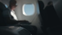 passenger on an airplane typing on laptop
