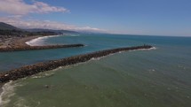 aerial view over a shore and rock jetty 