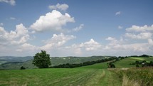Clouds moving over blue sky and fresh green landscape in countryside time lapse
