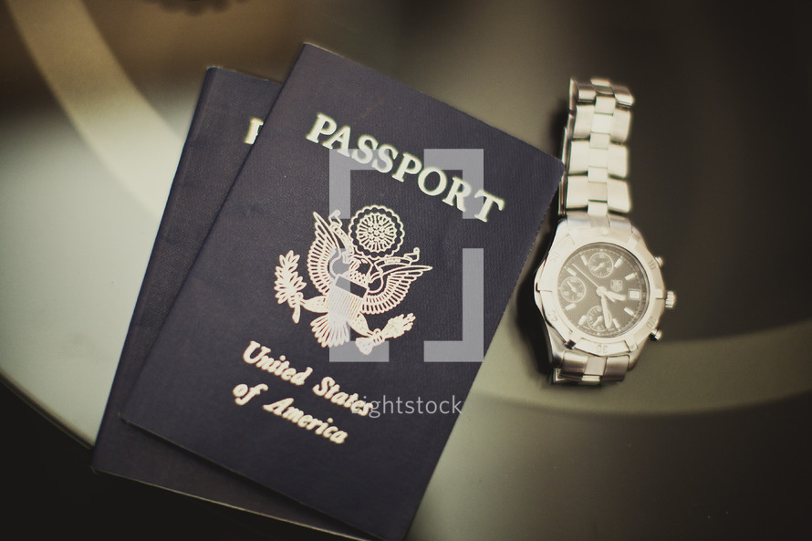 Two U.S. passports and a silver watch sitting on a table