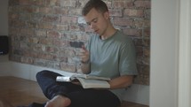 young man sitting on the floor reading the Bible 