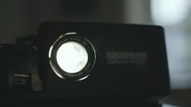 Looking into the lens of a slide projector and dust backlit by the lamp of the projector