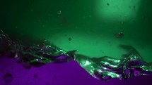 Beautiful mix of green and purple liquids of different densities in aquarium. Abstraction of colored fluid stirring in slow motion. Abstract colorful design.