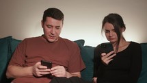 A Couple Sitting on the Sofa, Engrossed in their Smartphones - Close Up	