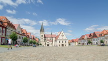 Time lapse of people and clouds in historic center of Bardejov in Slovakia. Zoom in on church

