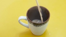 A top-view close-up of hot tea being poured into a cup.