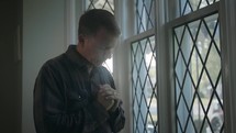 man praying at a window 