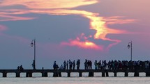 Timelapse of people walking on pier at sunset