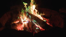 Close up panning shot of strange fire with green, blue, and orange flames. 