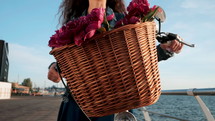 Young attractive woman with curly hair riding vintage bike near sea during sunrise or sunset