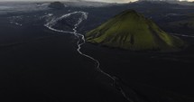 Drone view of rivers and glaciers surrounded by moss mountains in Iceland with scenic clouds in the background