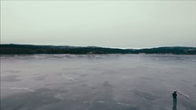a man standing on a frozen lake and ice skaters 