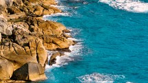 Aerial Top view of a transparent blue sea with beautiful waves. Aerial view seashore cliffs wave crashing on rocks