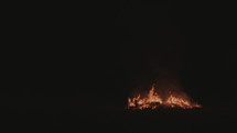 Wide shot of the end of a bonfire at night