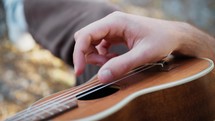 Smiling Boy Plays Ukulele Musical Instrument In An Outdoor Park