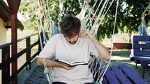 Man reading the Bible in a hammock chair outdoors