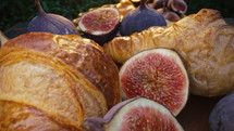 Camera moves between sliced halves of healthy juicy ripe figs and croissants rotating. Dolly slider extreme macro. Seasonal fruit details, Ficus carica. Amazing breakfast. High quality 4k footage