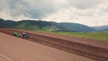Panoramic view of cultivate farm field with a tractor and planting organic food in spring farmland country