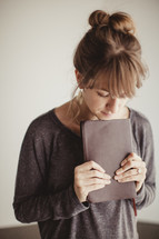 woman holding a Bible with her head bowed in prayer