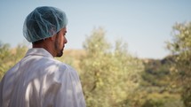 Scientist with lab coat staring at olive trees in the countryside 