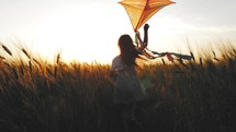 Childhood dream. Happy girl run with a kite in a field of wheat. Pretty girl playing with kite in wheat field on summer day. Happy family. Freedom of action. Childhood, lifestyle concept.