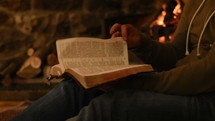 man reading a Bible fireside 