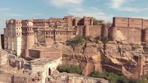 view of the majestic Mehrangarh Fort's facades and exterior walls surrounded by birds of prey in Jodhpur, Rajasthan, India - Aerial establishing shot