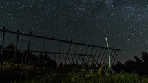 Starry night sky with milky way galaxy stars moving over old wooden cart Time-lapse
