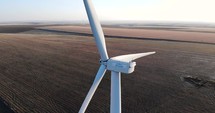 Aerial orbit of Wind Turbines Standing On The Field With Close Up View Of Spinning Propeller. Clean And Renewable Energy. 