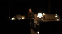 girl sitting by a lamp in a dark room reading a Bible 