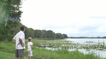 father and son standing together looking out over a lake 