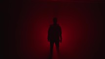 silhouette of a person walking in a tunnel of red light 