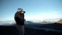 man on a mountaintop in Hawaii taking pictures with a camera 