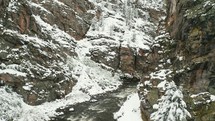 Drone view through snow covered rock formations and a river in the Colorado mountains.