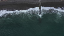 Slow aerial zoom out of waves crashing on the beach