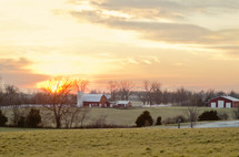 A field with barns and a sunset.