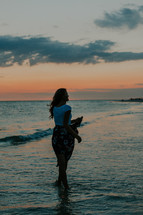a young woman walking on a beach at sunset 