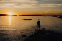 a man standing on a shore at sunset 